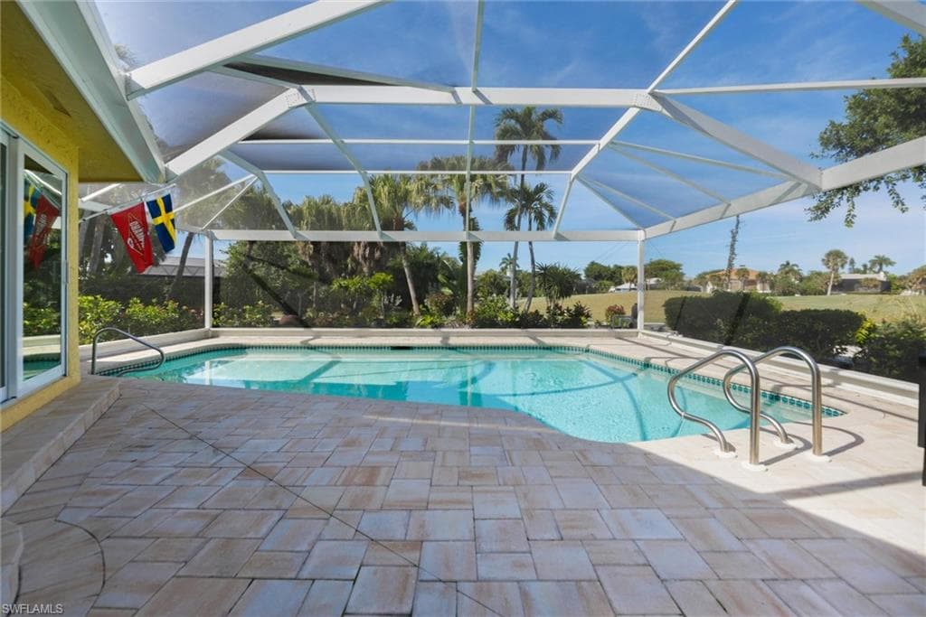 Swimming pool with a sunroom, a patio, and glass enclosure