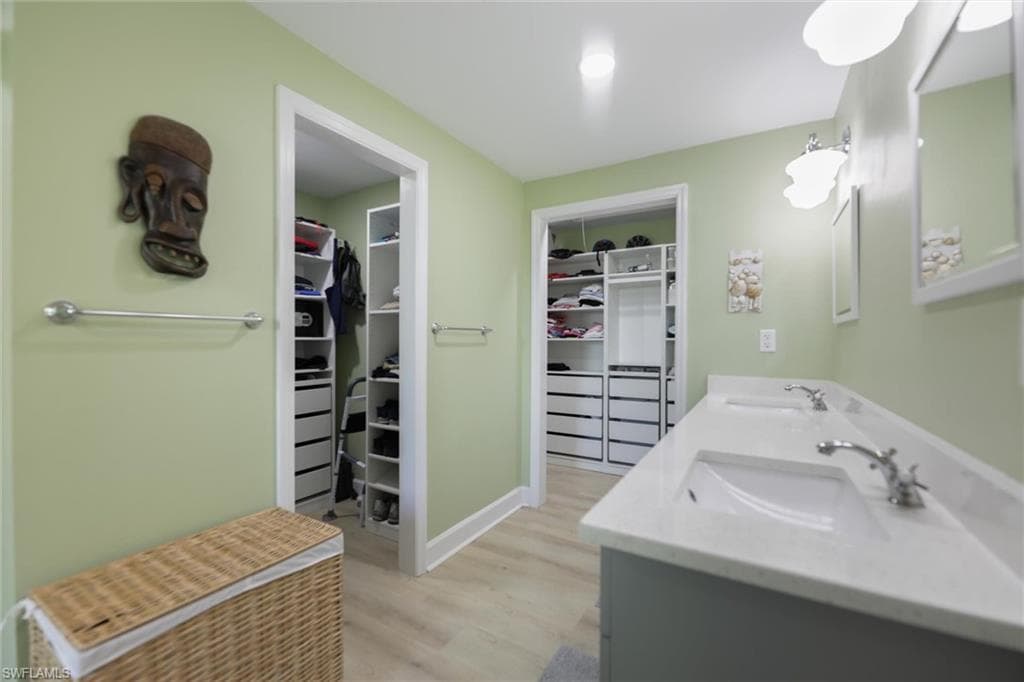 Full bathroom with two spacious closets, light wood-style floors, and double vanity