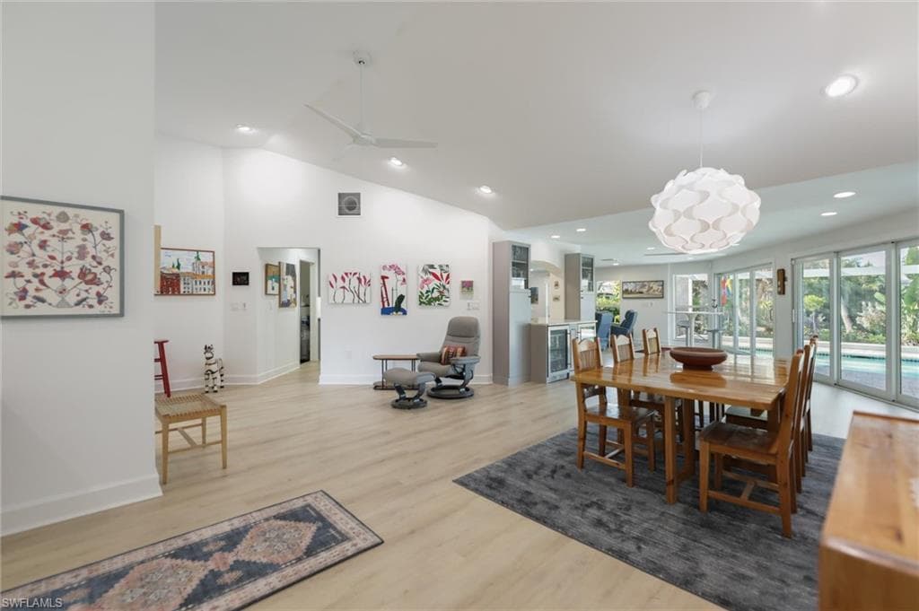 Dining area with lofted ceiling, light wood-type flooring, recessed lighting, wine cooler, and a ceiling fan