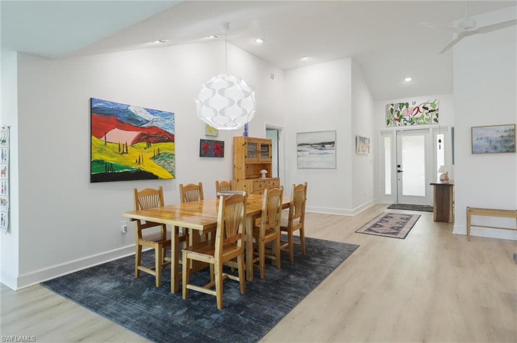 Dining area with high vaulted ceiling, light wood-style floors, and ceiling fan