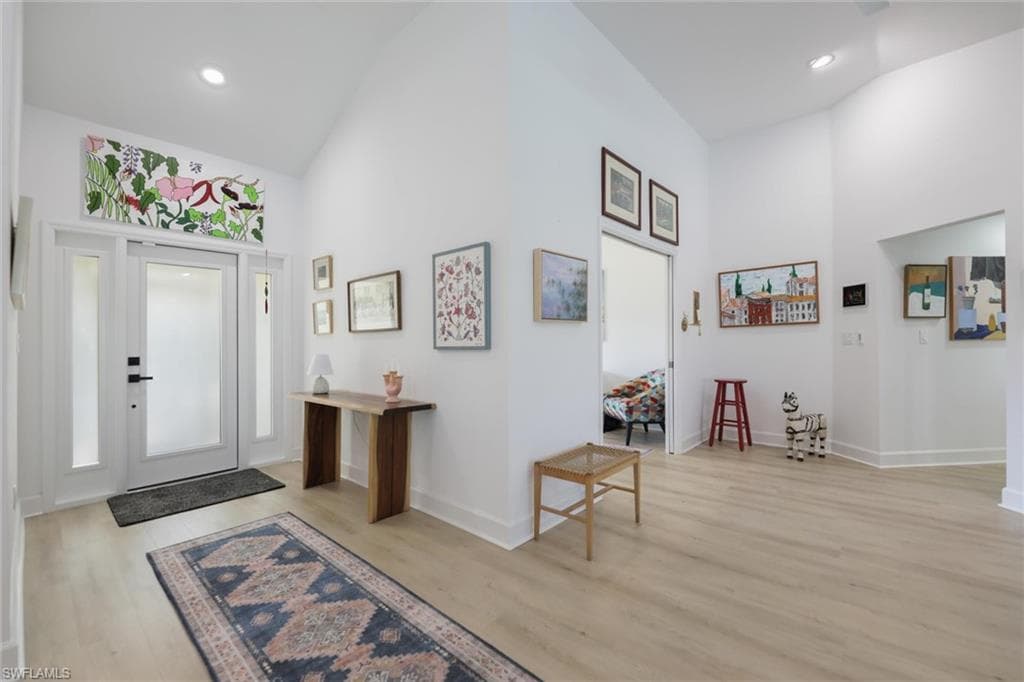 Foyer with high vaulted ceiling, light wood-style floors, and recessed lighting