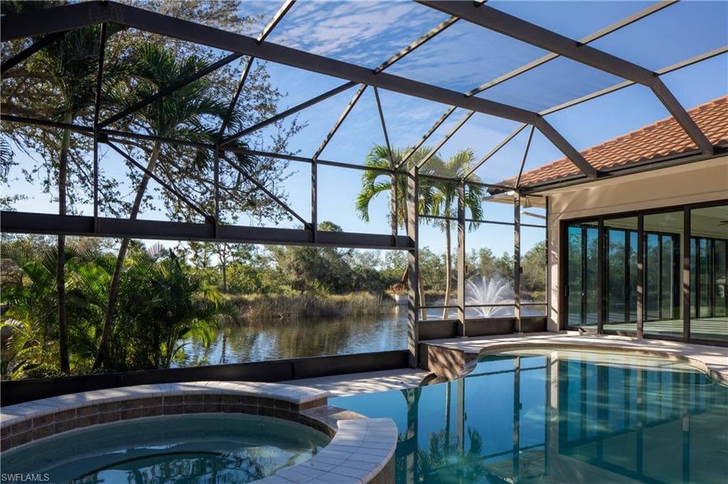 View of swimming pool with a sunroom, a pool with connected hot tub, a lanai, a patio area, and a water view