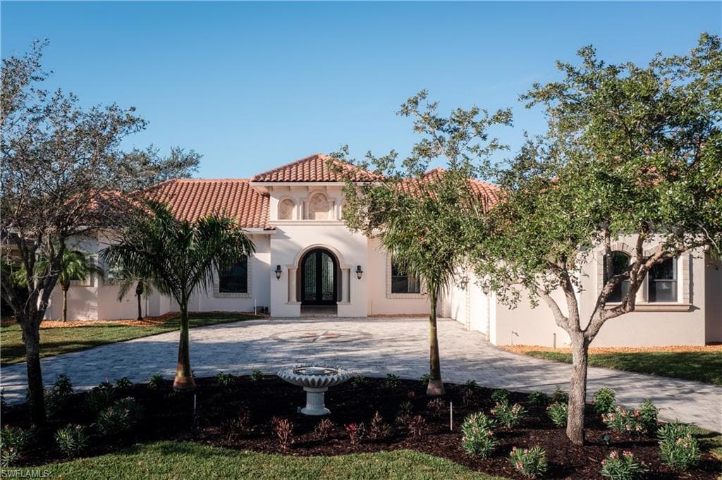 Mediterranean / spanish home with french doors, curved driveway, and stucco siding