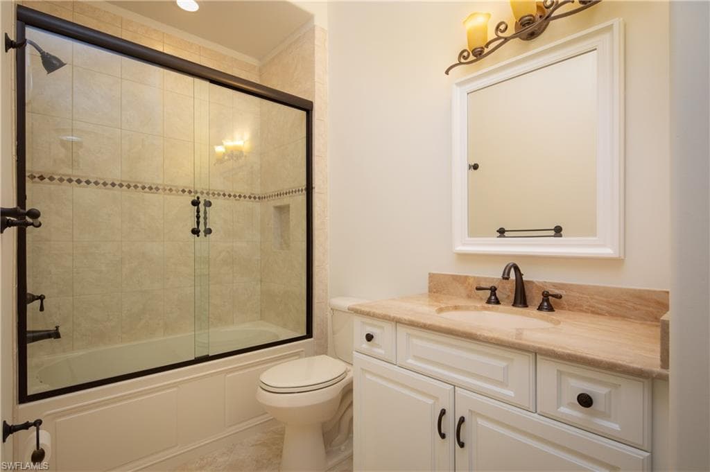 Full bathroom featuring vanity and shower / bath combination with glass door