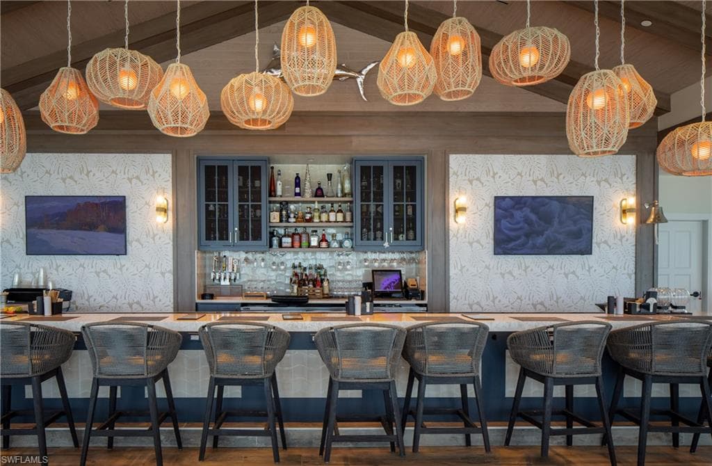 Community bar area featuring open shelves, hanging light fixtures, wallpapered walls, glass insert cabinets, and a wooden ceiling with exposed beams