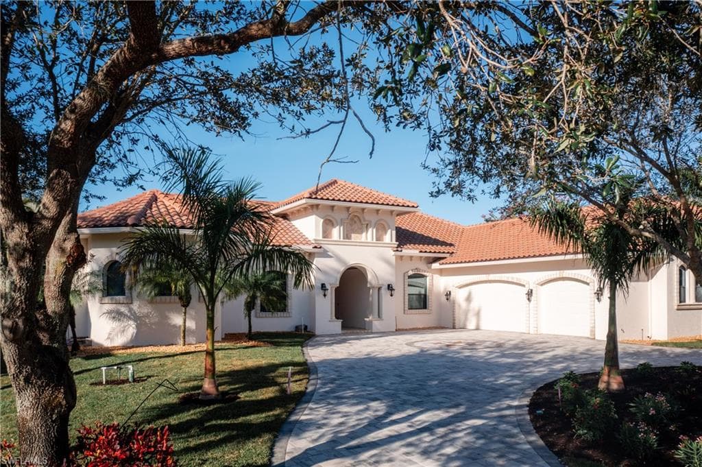 Mediterranean / spanish home featuring decorative driveway, an attached garage, stucco siding, and a tiled roof