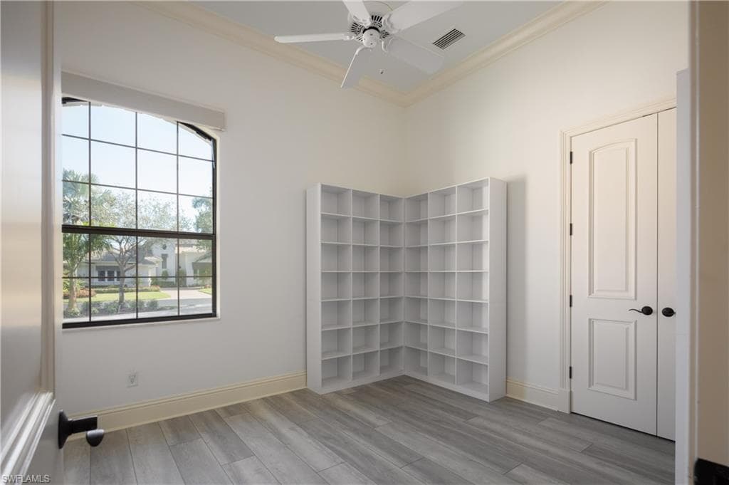 Spare room featuring light wood-style flooring, ornamental molding, and ceiling fan
