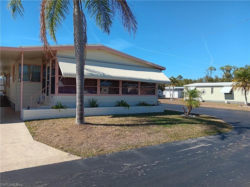 Manufactured / mobile home featuring a carport, driveway, and a porch