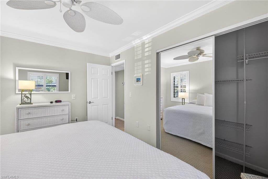 Carpeted bedroom with crown molding and ceiling fan