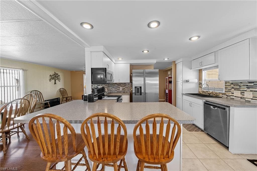Kitchen with plenty of natural light, stainless steel appliances, a peninsula, and white cabinetry