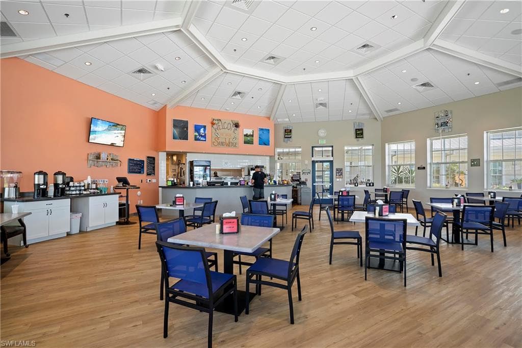 Dining space featuring a high ceiling, light wood-style floors, and beam ceiling