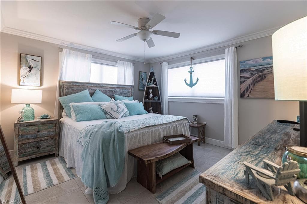 Bedroom with light tile flooring, ornamental molding, baseboards, and ceiling fan