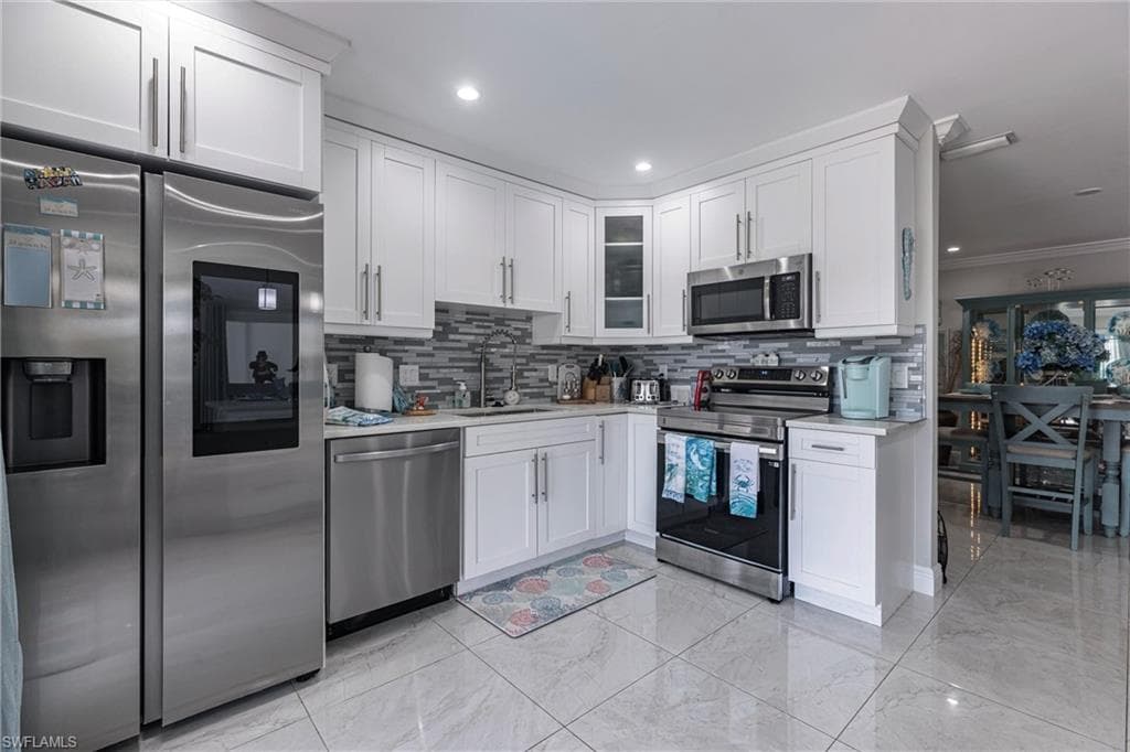 Kitchen featuring a sink, white cabinetry, light countertops, and appliances with stainless steel finishes