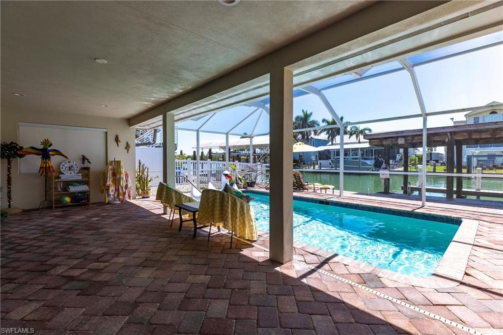 Pool with screen enclosure, a water view, and a patio area