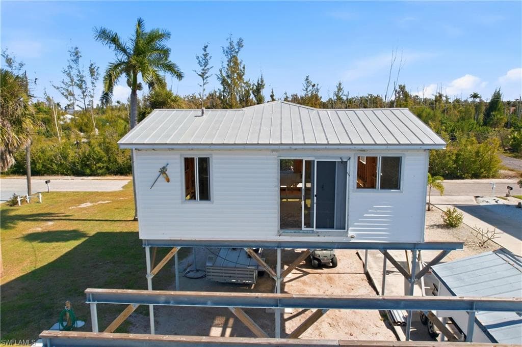 Rear view of house with a standing seam roof, a carport, a patio area, and a metal roof