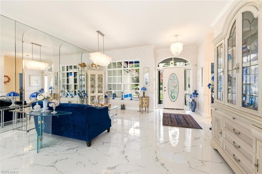 Entrance foyer with suspended lighting, crown molding, and light marble finish floors