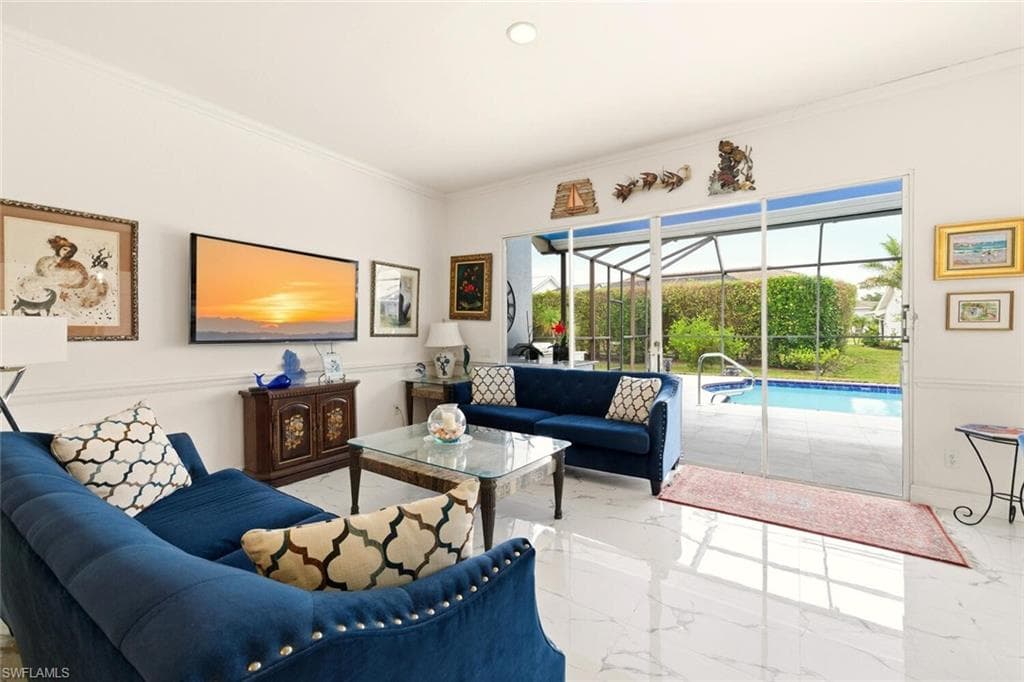 Living area featuring a sunroom, ornamental molding, marble tiled floors, and recessed lighting
