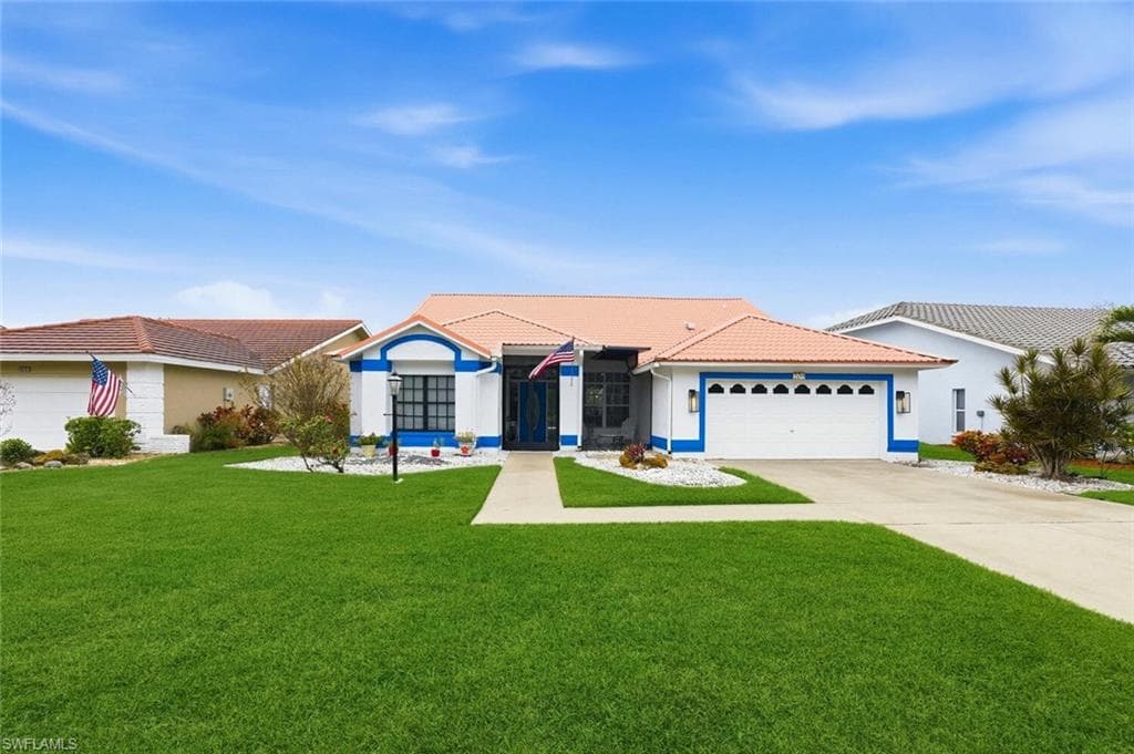 Ranch-style house with a front yard, concrete driveway, a tile roof, a garage, and stucco siding