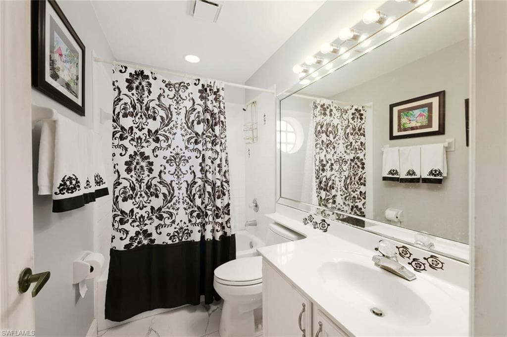 Bathroom with vanity, shower / bath combo with shower curtain, and light marble finish flooring