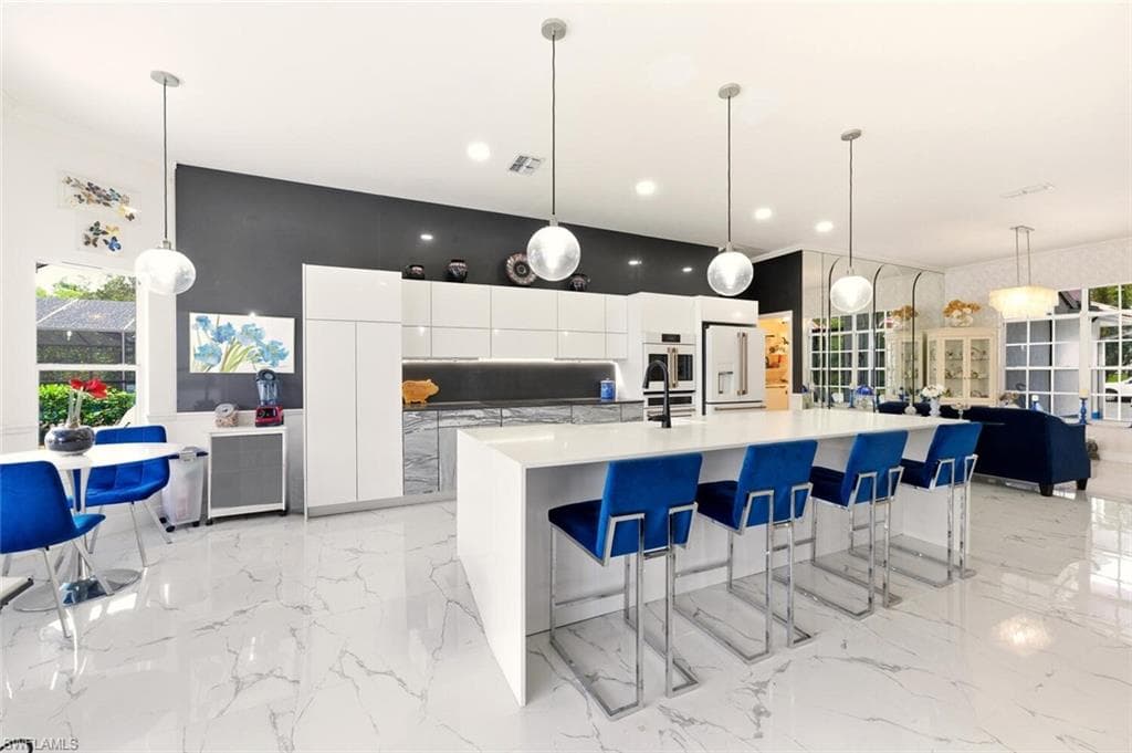 Kitchen with white cabinetry, decorative light fixtures, modern cabinets, a breakfast bar area, and a large island