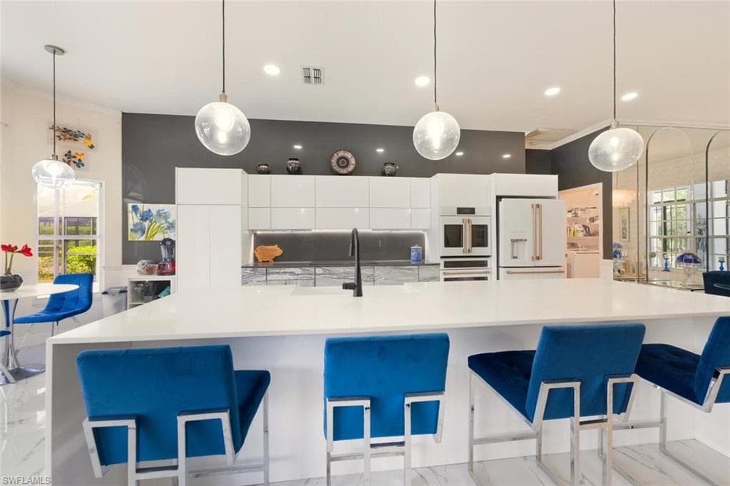 Kitchen with plenty of natural light, modern cabinets, white cabinets, and decorative light fixtures