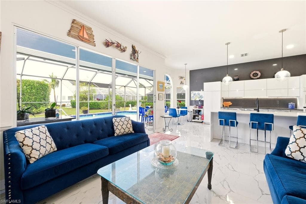 Living room with a sunroom, light marble finish flooring, and crown molding