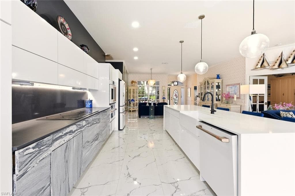 Two tone kitchen featuring modern cabinets, hanging light fixtures, white appliances, wallpapered walls, and two tone cabinets