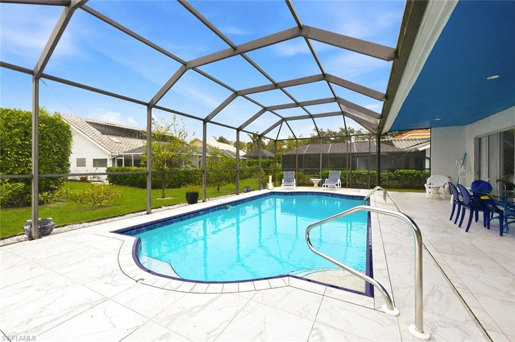 Swimming pool with a sunroom, a lawn, glass enclosure, and a patio area