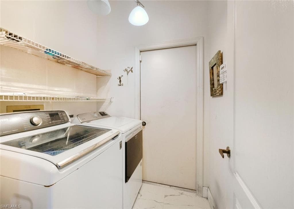 Laundry area with light marble finish flooring and separate washer and dryer