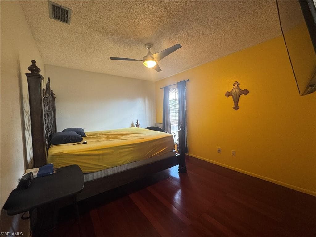 Bedroom with dark wood-style floors, a textured ceiling, and ceiling fan