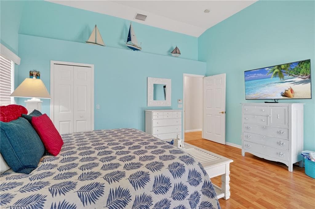 Bedroom featuring light wood-type flooring, a closet, and high vaulted ceiling