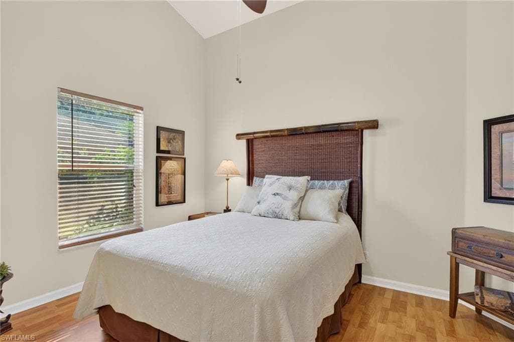 Bedroom featuring light wood-type flooring, high vaulted ceiling, and a ceiling fan