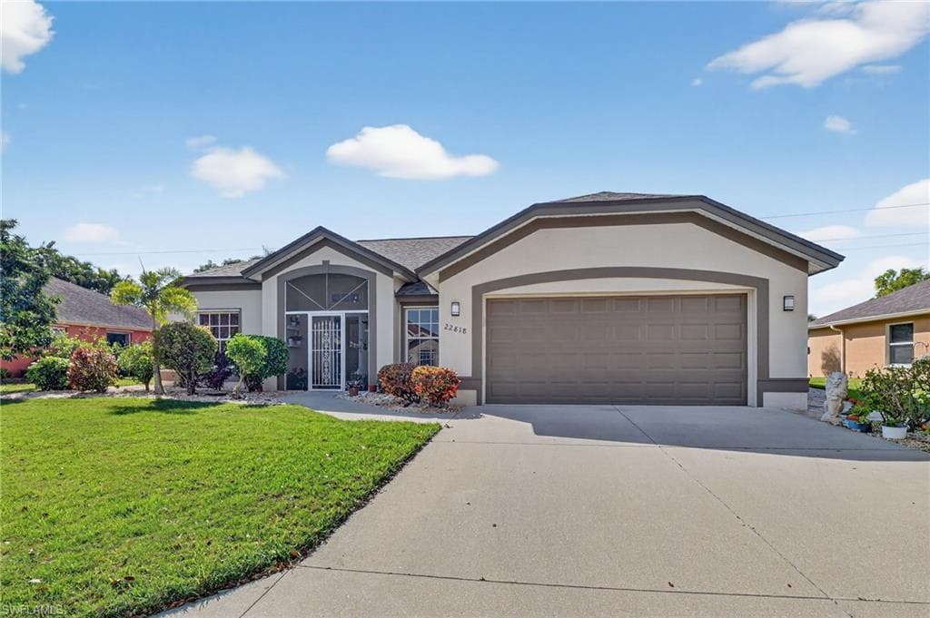 Ranch-style home with stucco siding, driveway, a front yard, and an attached garage