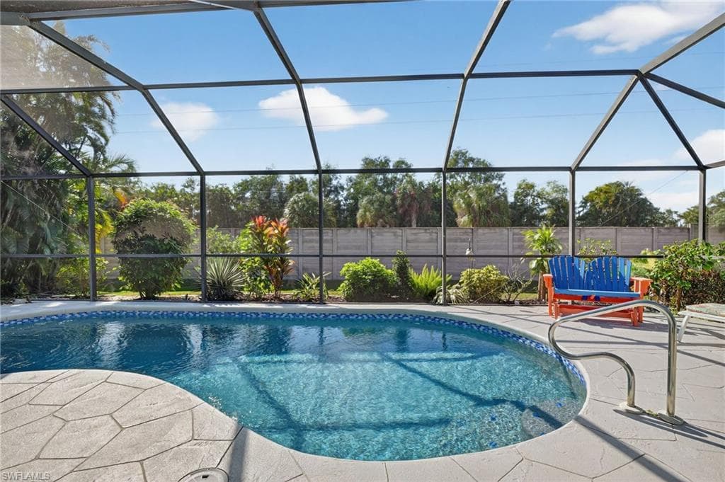 View of swimming pool with screened lanai and privacy fence