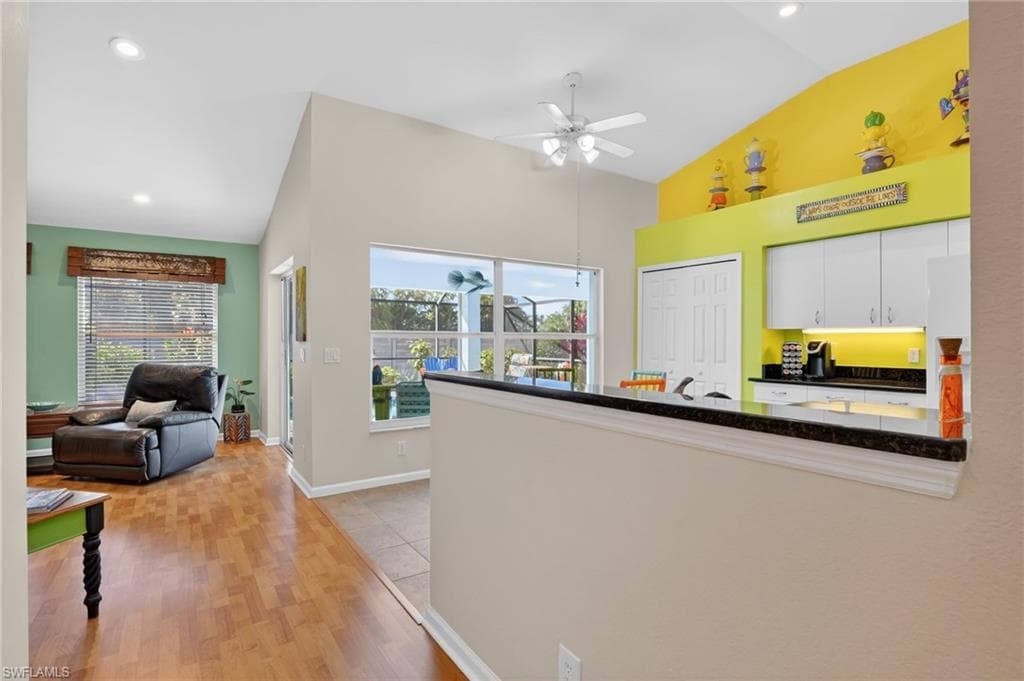Kitchen featuring white cabinets, high vaulted ceiling, a ceiling fan, and light wood finished floors