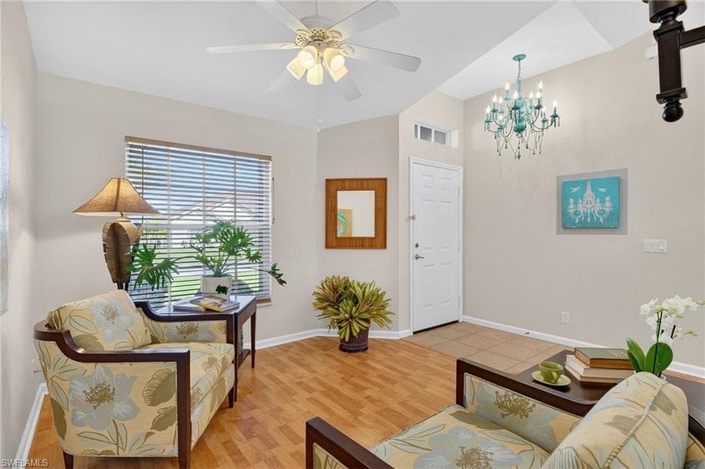 Sitting room with light wood-style floors, a ceiling fan, vaulted ceiling, and a chandelier