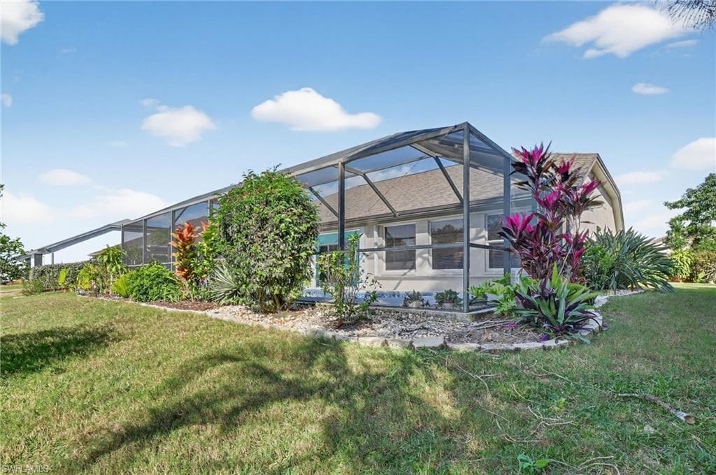 Back of house with a sunroom, glass enclosure, and a yard