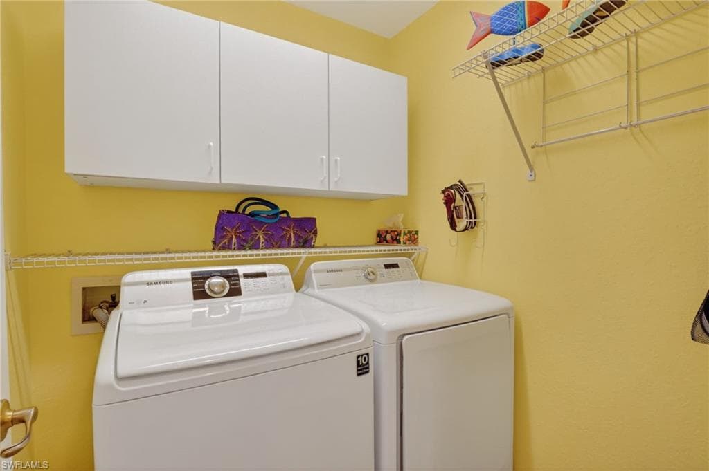 Washroom featuring cabinet space and washing machine and clothes dryer