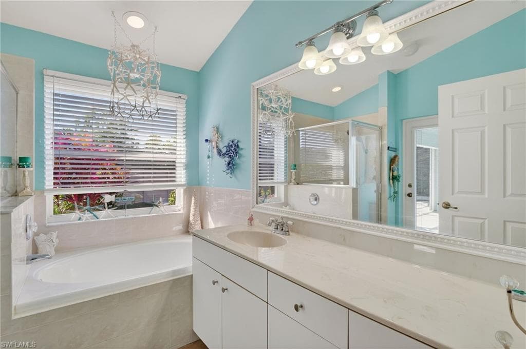 Full bathroom with a chandelier, a bath, a stall shower, vanity, and lofted ceiling