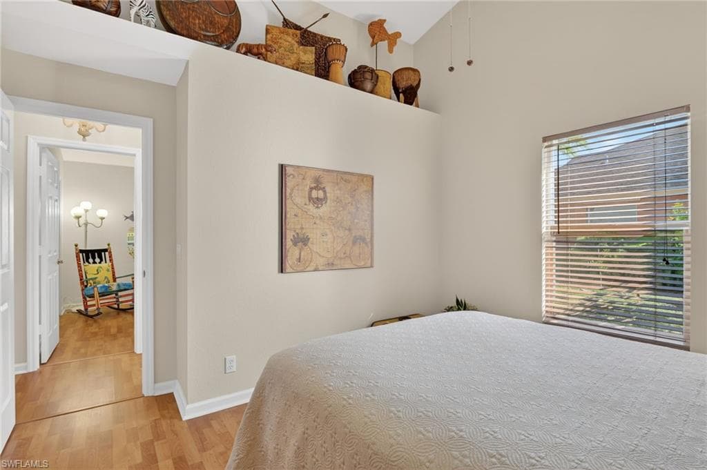Bedroom featuring light wood-style floors, a high ceiling, and a chandelier