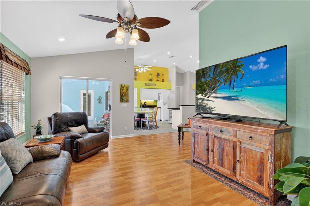 Living room with light wood finished floors, high vaulted ceiling, a ceiling fan, and recessed lighting