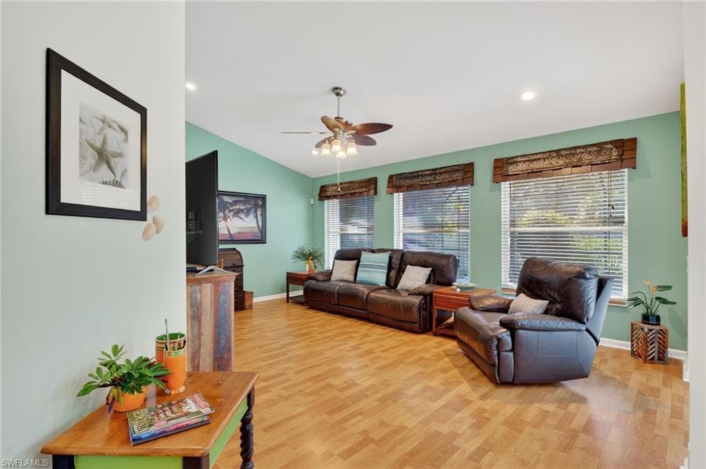 Living room with light wood-type flooring, a ceiling fan, recessed lighting, and vaulted ceiling