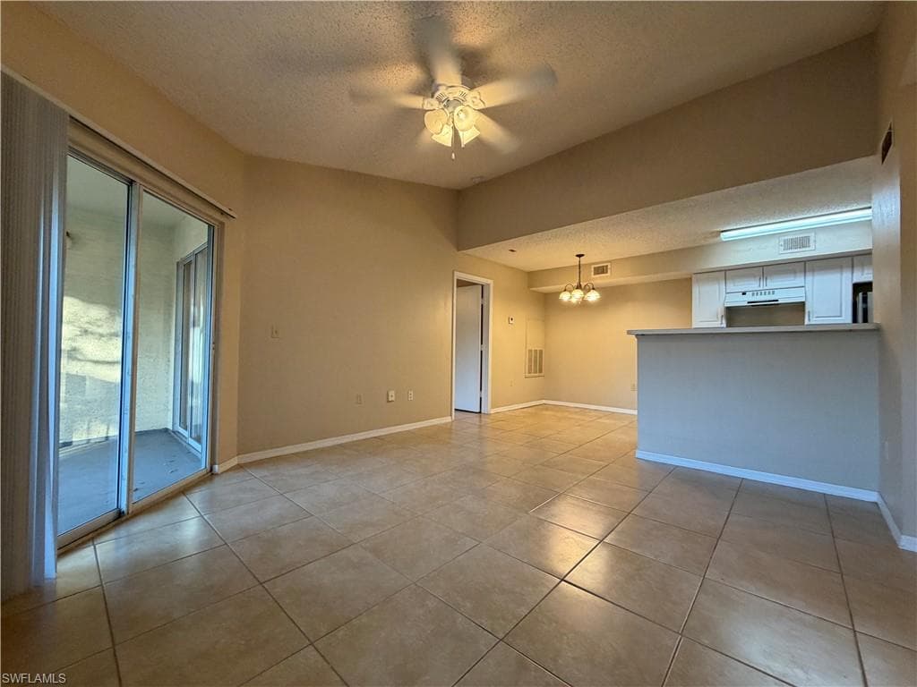 Unfurnished room with a textured ceiling, a chandelier, ceiling fan, and light tile patterned floors