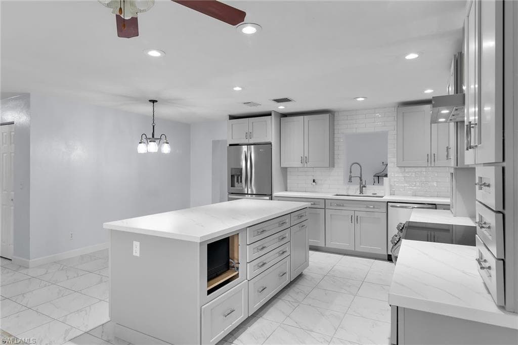 Kitchen with light marble finish floors, recessed lighting, light stone counters, stainless steel fridge with ice dispenser, and a center island