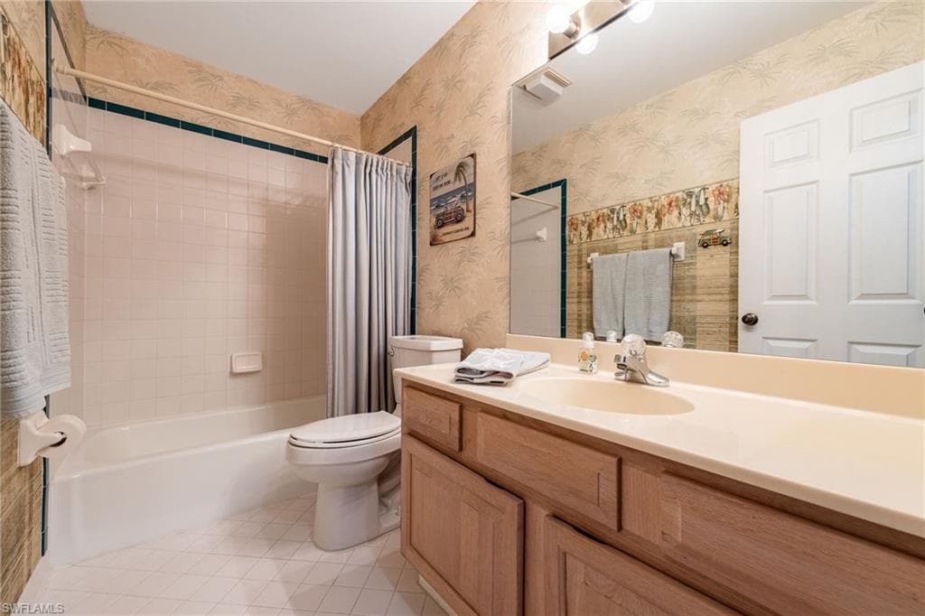 Full bathroom featuring vanity, shower / tub combo, light tile patterned floors, and wallpapered walls