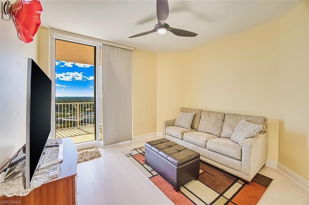 Living area with expansive windows, wood finished floors, and ceiling fan