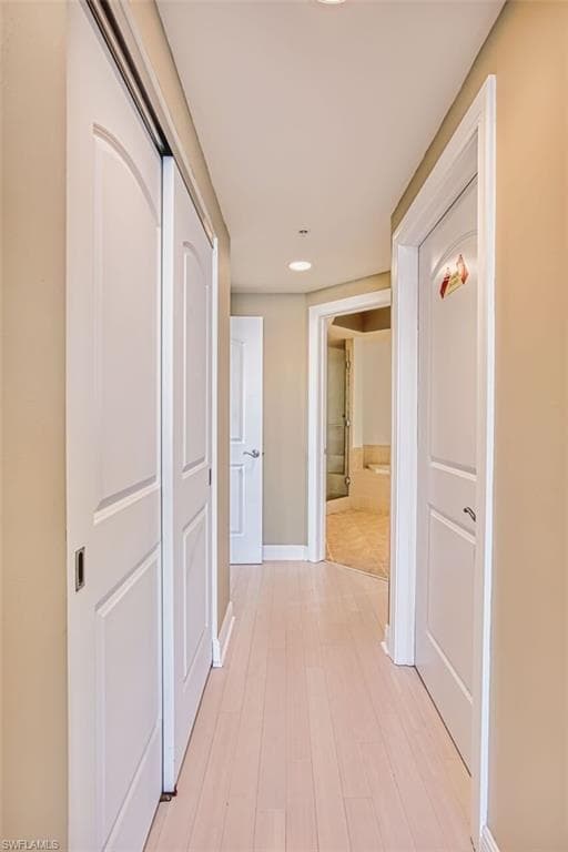 Hallway with light wood-style floors and recessed lighting