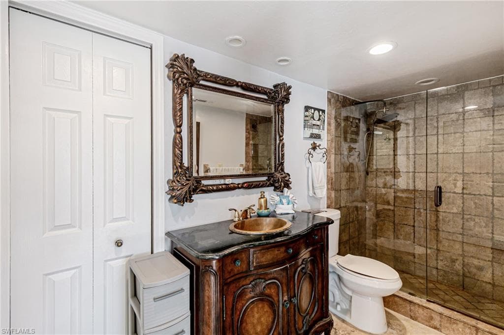 Full bathroom with vanity, a stall shower, and a closet