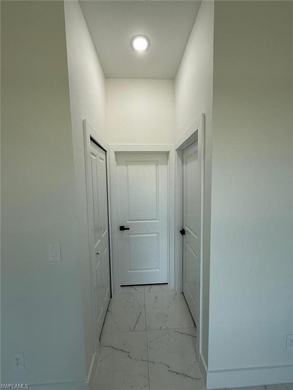 Hallway featuring light marble finish floors