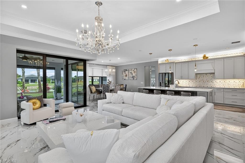 Living room with marble tiled flooring, ornamental molding, a chandelier, and recessed lighting